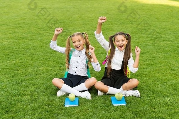 假期已经开始了。快乐的孩子们在户外庆祝节日。小女孩们坐在绿色的草地上。学校假期。暑假和假期。休闲和自由<strong>时间</strong>。学校<strong>放假</strong>了。