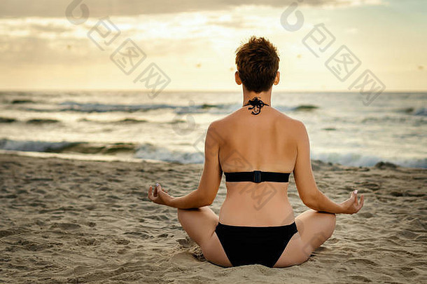 美丽的女人黑色的泳衣冥想海滩日落