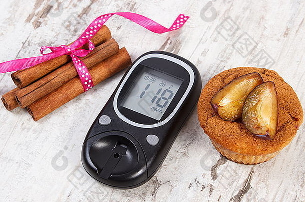 血糖仪，在古老的乡村木制背景上放着李子和肉桂棒的松饼，糖尿病的概念和美味的甜点