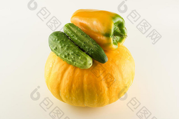 巨大的黄色南瓜，白色背景上有辣椒和黄瓜