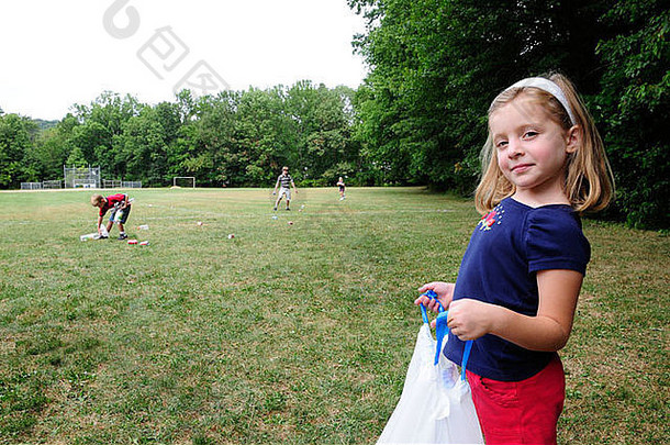 女孩持有垃圾袋帮助社区服务努力挑选可回收的垃圾公园场
