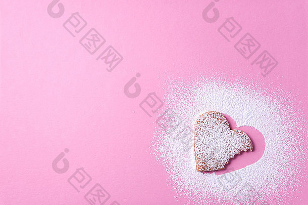 心形状的饼干糖糖衣粉红色的纸背景咬