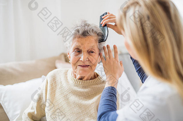 一位健康访客正在家里梳理老妇人的头发。。