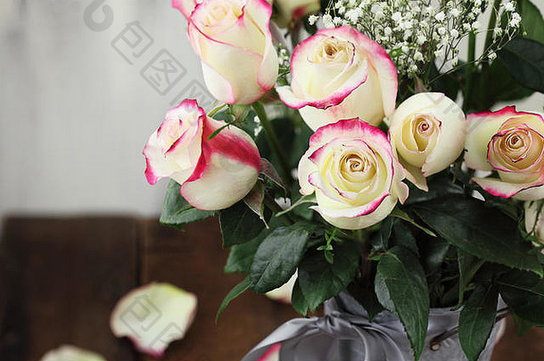一个金属农舍风格的花瓶里有一束美丽的红玫瑰和白玫瑰，带有婴儿的气息。选择重点放在前景中的玫瑰上，带有极端的沙勒色