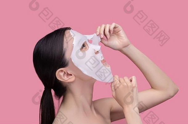 年轻的女人应用纺织面部美面具