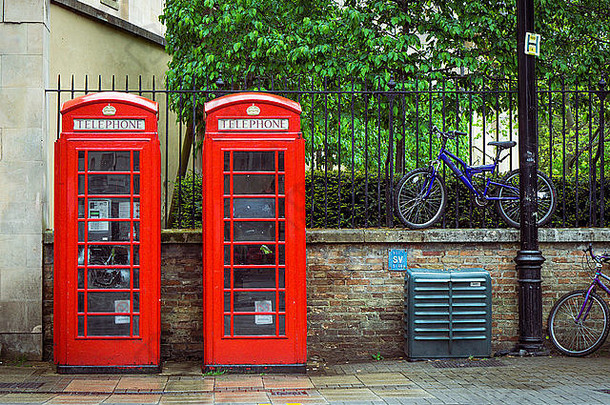 背景中有两个红色的英国电话亭和自行车