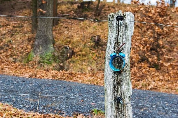一个生锈的旧闹钟的外壳悬挂在农村秋天风景区的木栅栏柱上