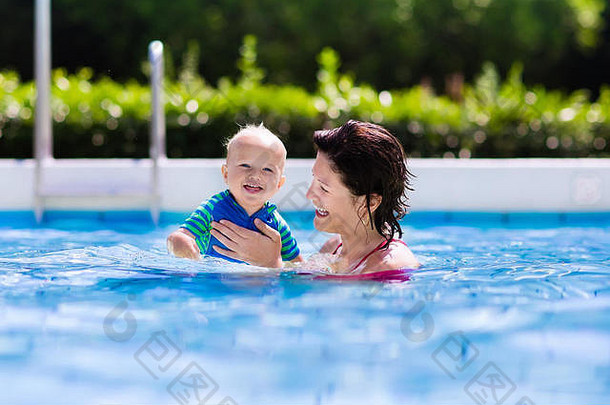 在炎热的<strong>夏日</strong>，快乐的年轻母亲在室外<strong>游泳</strong>池里和她的孩子玩耍。孩子们在家庭假期学习<strong>游泳</strong>。