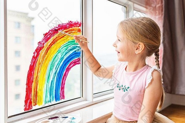 <strong>儿童</strong>绘画彩虹在2019冠状病毒疾病在家检疫。靠近窗户的女孩。在家社交媒体上开展预防冠状病毒的活动，让我们共同努力