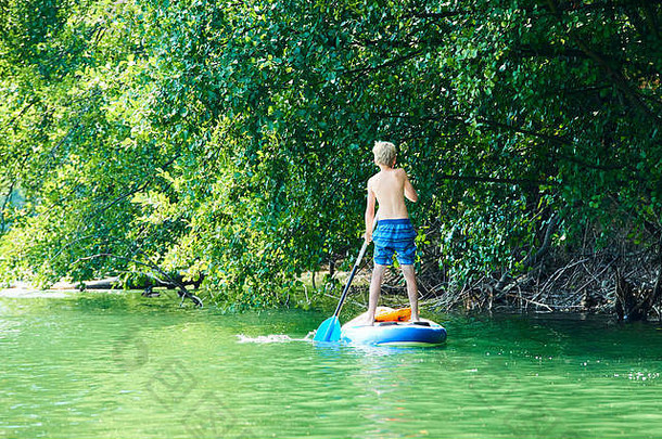 划船者。小男孩在站立的桨板上划水。健康的生活方式。水上运动、探险营SUP冲浪之旅，活跃家庭夏日