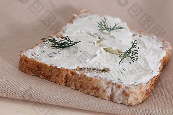 木桌上一块布上放着奶酪的面包。