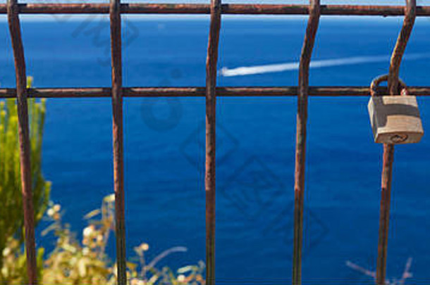 爱锁在欧洲葡萄牙马德拉岛Funchal海滨散步的围栏上，背景是蓝色的北大西洋