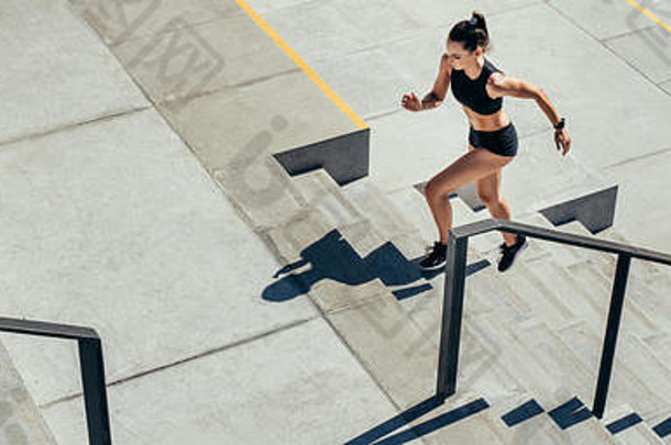 年轻女子跑<strong>上台</strong>阶作为日常锻炼。穿着运动服在室外楼梯上锻炼的运动员。
