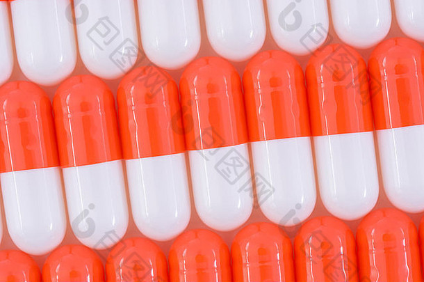 药丸特写-胶囊形式制成的明胶。橙色/白色药片。比喻在高药价问题上与美国制药公司较量。