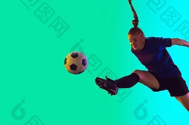 年轻的女足球足球球员长头发运动服装踢球目标跳梯度背景霓虹灯概念健康的生活方式专业体育运动运动运动