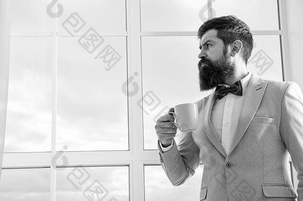 现代商人。体贴的胡子男人喝咖啡。穿着现代正式服装的商人。现代生活。窗口的商人。未来的成功。早晨的灵感。空间。现代办公室。
