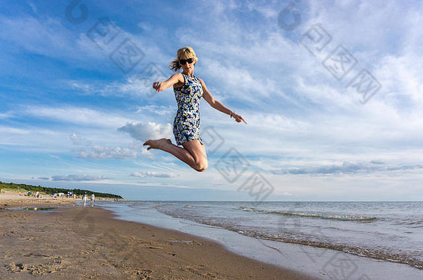 快乐年轻的女人短衣服跳海滩夏天<strong>蓝色</strong>的天空