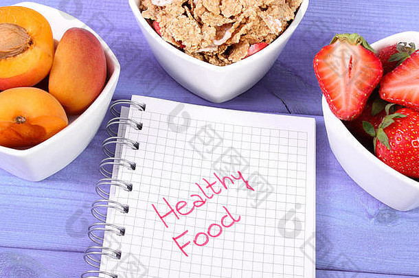 新鲜成熟的水果、小麦和黑麦片以及用于在黑板上写笔记的笔记本，健康营养和生活方式的概念