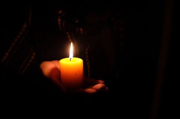 妇女们在黑暗中手持燃烧的蜡烛