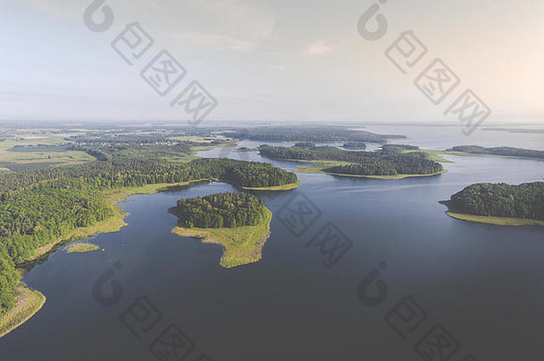 在夏日阳光明媚的早晨鸟瞰绿色岛屿和云层。波兰的马苏里亚湖区。