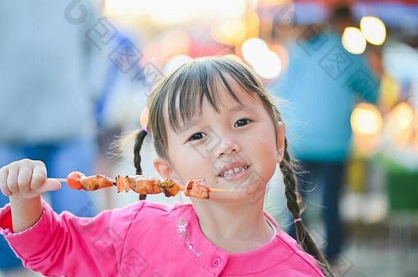 亚洲小女孩在曼谷街头散步，晚上买烧烤和吃街上的食物