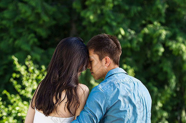 水平照片年轻的成人夫妇触碰额头额头绿色树背景