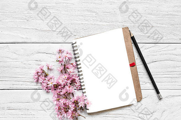 模拟空白纸笔记本，粉红色的春天樱花枝，有复印空间。顶视图。平铺