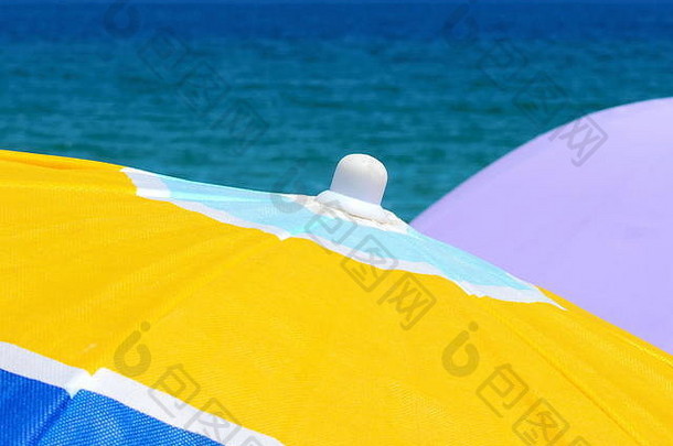 靠近水面的沙滩伞。海滩上的沙滩伞。多彩的节日背景。海滩上鲜艳的颜色。