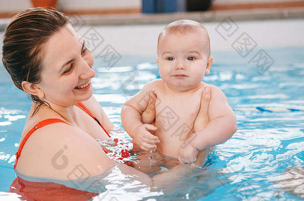 白人白人母亲训练她的新生婴儿在游泳池中漂浮。婴儿在水中潜水。健康积极的生活方式。家庭活动与早期疾病