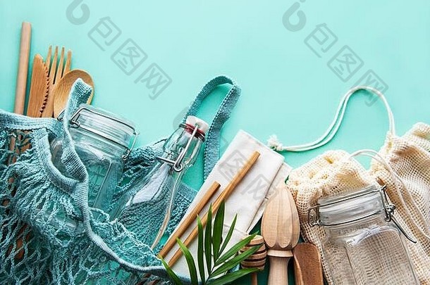 零浪费、无塑料、环保的生活方式。以淡绿色为背景的棉网袋、玻璃瓶、罐子和竹餐具。平铺。