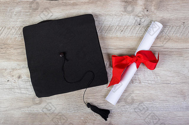 毕业帽、学位纸帽配上木桌毕业概念。
