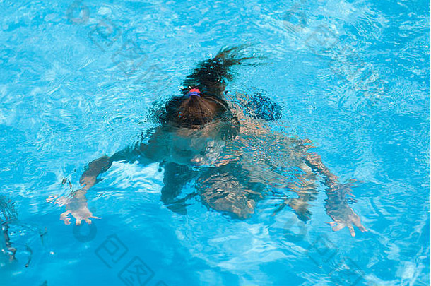 暑假，小女孩在碧蓝的游泳池里潜水