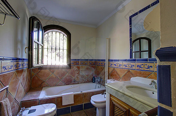 西班牙浴室浴缸上方的窗户打开，陶土瓷砖墙至护墙板高度