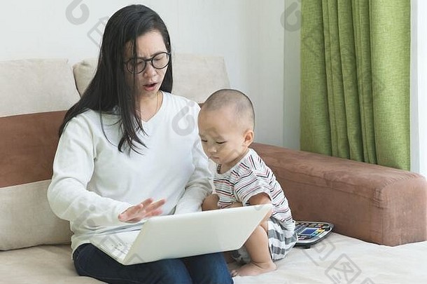 年轻的美丽的女人坐着沙发令人不安的孩子在家中上班移动PC工作首页社会距离概念