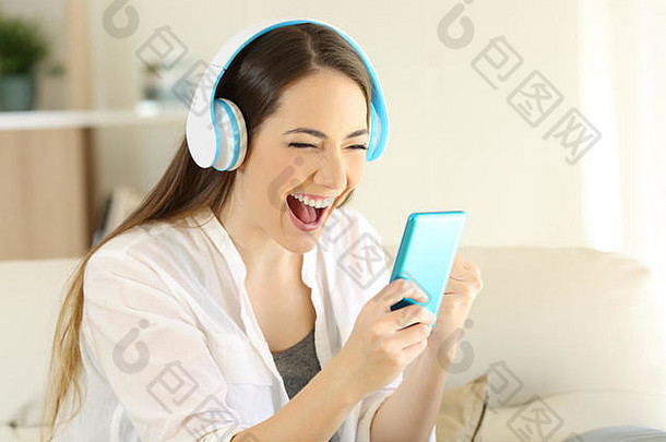 一个兴奋的女孩在智能手机上寻找在线服务，在家听音乐的照片