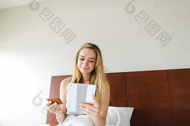 年轻的金发女郎用平板电脑在线购物，用支付。