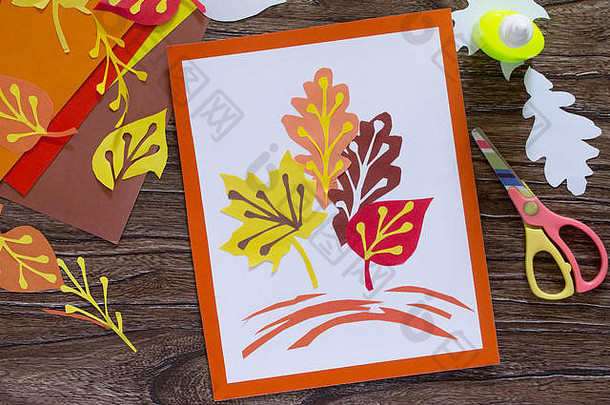 木制背景上的彩纸秋天的叶子。儿童纸工艺品。儿童艺术项目。