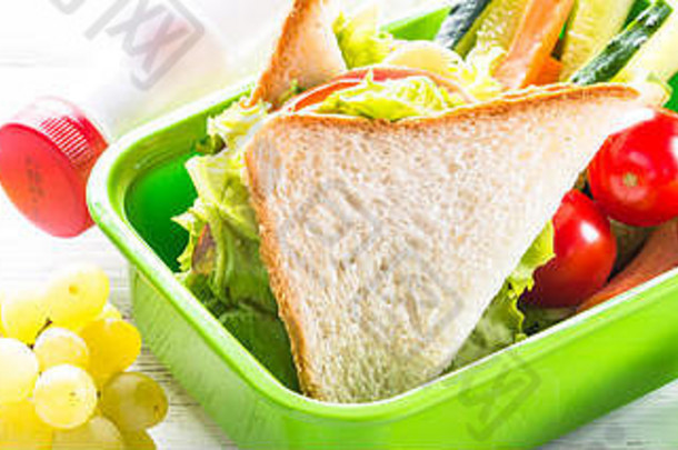 午餐盒里有三明治、蔬菜、香蕉、水、坚果和水果