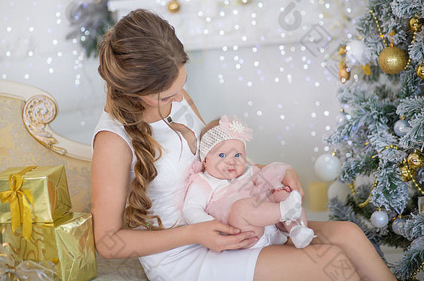 妈妈妈妈带着一个可爱漂亮的小女儿，坐在圣诞树旁玩耍、<strong>咕咕叫</strong>。