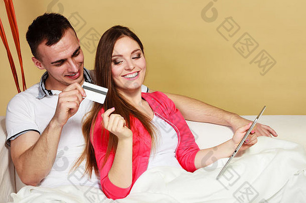 <strong>购物</strong>消费主义休闲与人的观念。一对年轻夫妇在家里用平板电脑和在沙发上上网<strong>购物</strong>