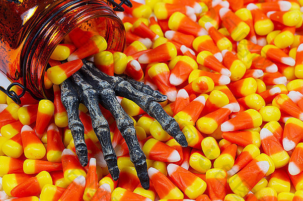特写镜头：一只可怕的手从罐子里伸出来，伸进一堆玉米糖里