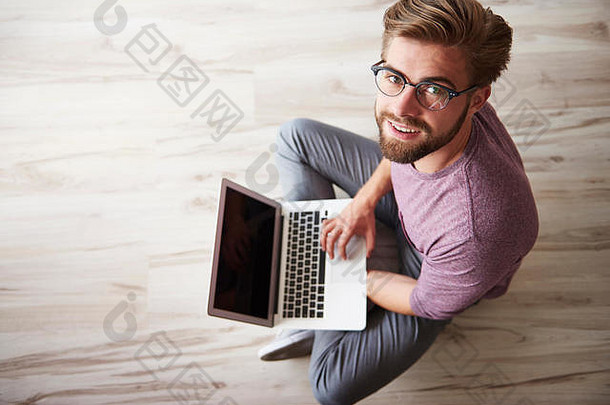 坐在地板上使用笔记本电脑的男人