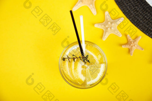 假日和饮酒的概念。冷鸡尾酒，柠檬水加柠檬薄荷，放在黄色桌子上的玻璃杯里。夏季背景。排毒水。