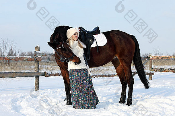 美丽的俄罗斯女孩在冬天牵着一匹大赛马