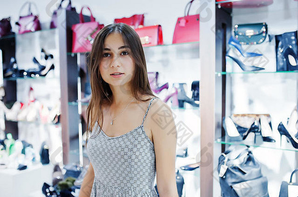 一位穿着灰色衣服的漂亮女人在鞋袋店的画像。