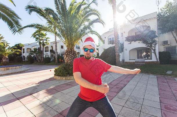 节日与人的概念-戴圣诞帽的滑稽男子在户外跳舞
