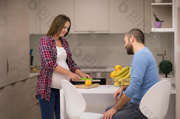 年轻怀孕夫妇在厨房烹饪食物水果柠檬汁，生活方式健康怀孕快乐生活理念