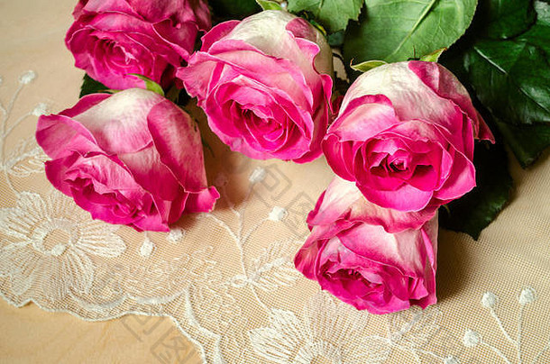 刺绣镂空面料，带有一束华丽的玫瑰和花瓣，沿边缘涂上白色和粉色，顶部与地面成一定角度