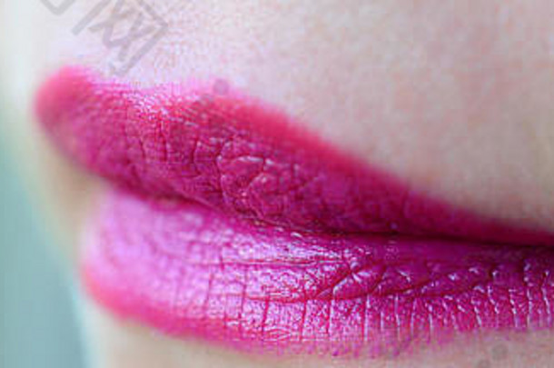 用美丽的紫红色唇膏贴近美丽的女人嘴唇。浅景深