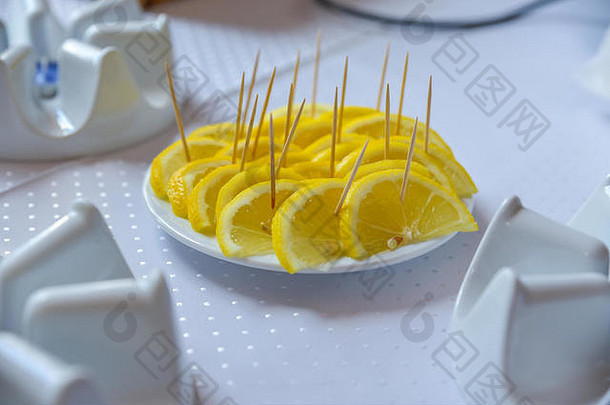 黄色的柠檬片放在模糊的桌子上的白色平板上